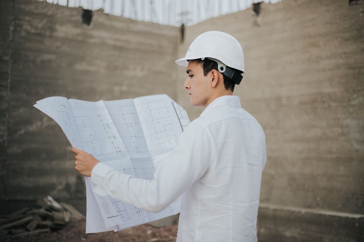Engenheiro civil analisando planta em canteiro de obras